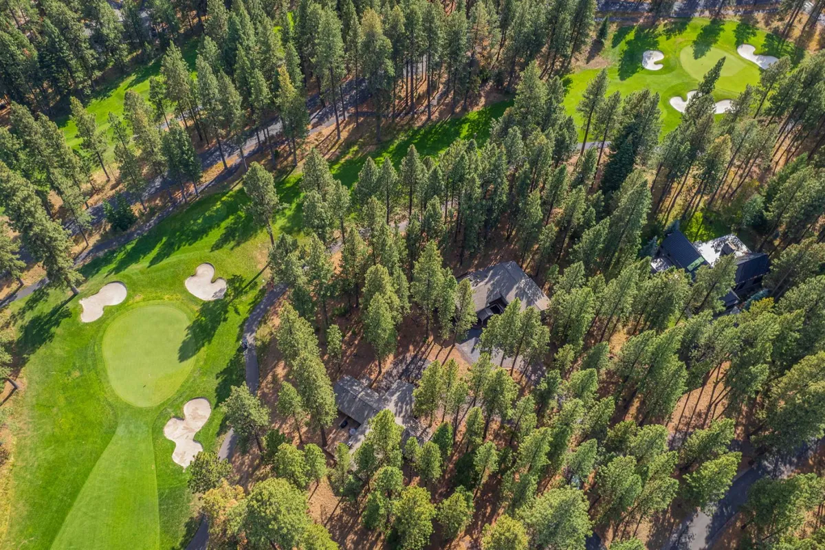 A tranquil scene of the golf course with lush green fairways, trees bordering the edges, and homes visible in the background. The open space conveys a sense of relaxation and the opportunity for lakeside walks and outdoor fun.