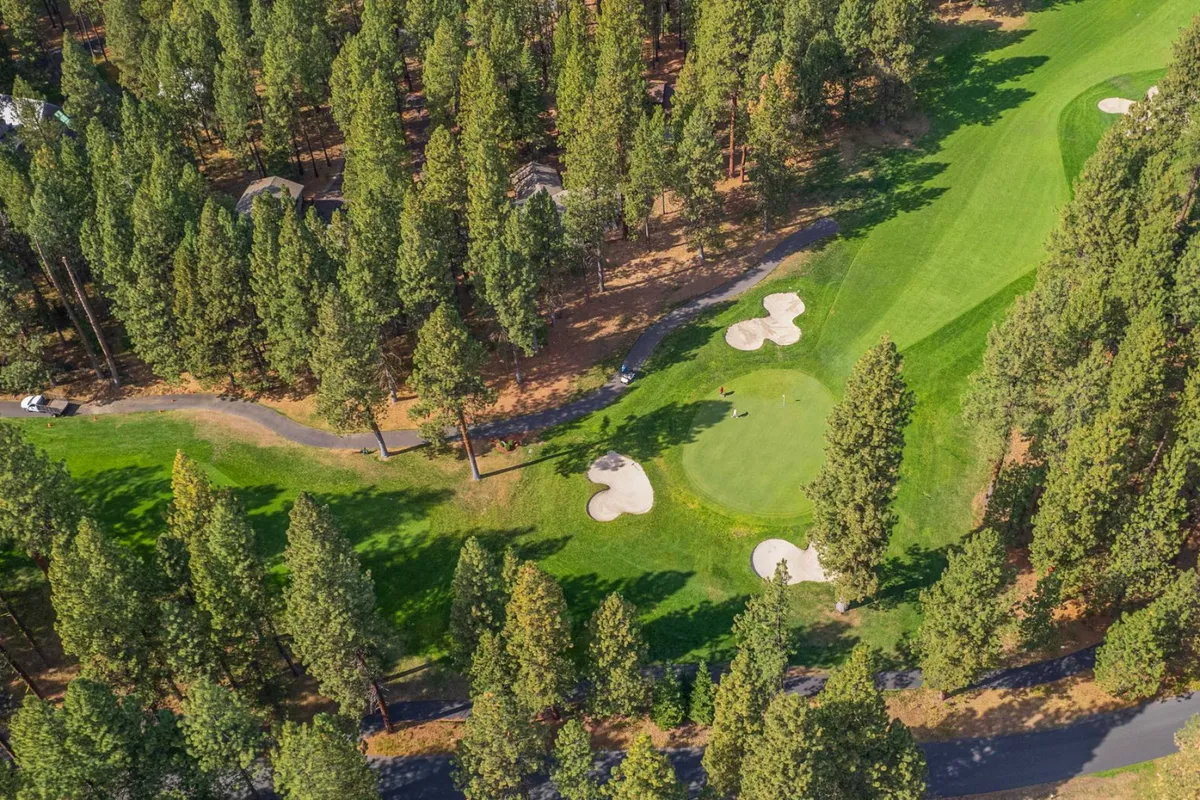 A sweeping view of the golf course greens, complete with sand bunkers and framed by surrounding pines. The expansive scene conveys the tranquil, scenic quality of the course and the leisure activities it offers.